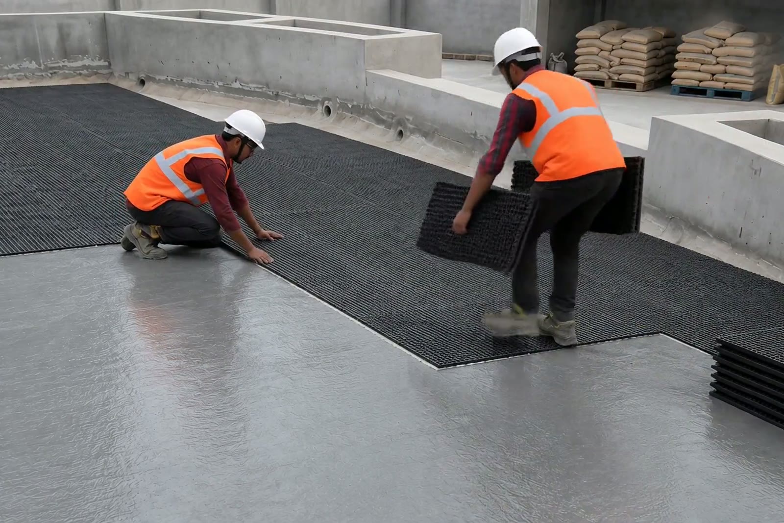 Crew laying RDC-20 drain cell boards on a waterproofed podium deck